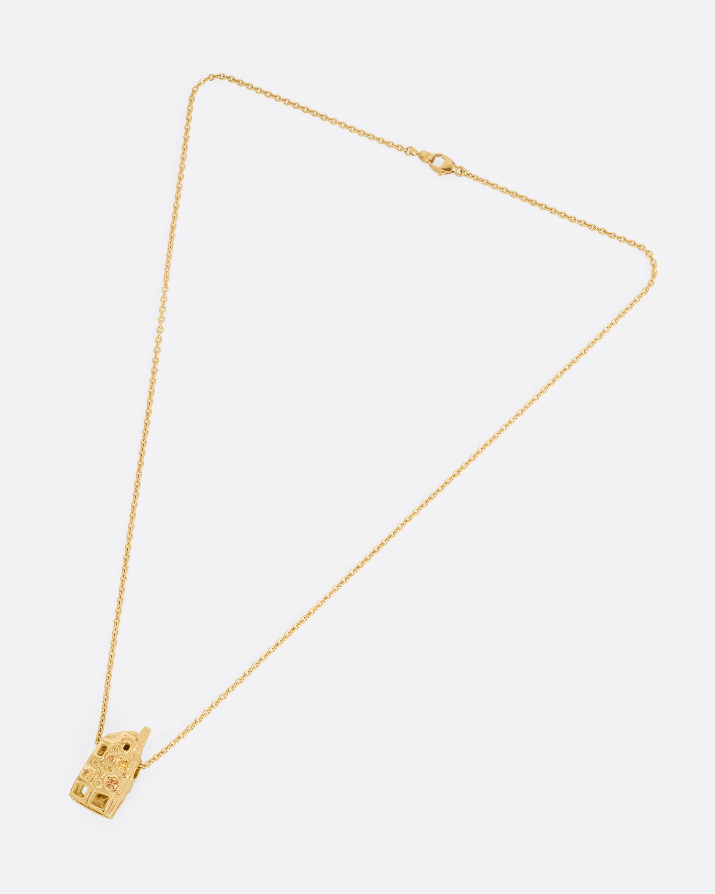 A yellow gold house-shaped pendant with multi-colored diamonds, on a cable chain, shown from the front. 