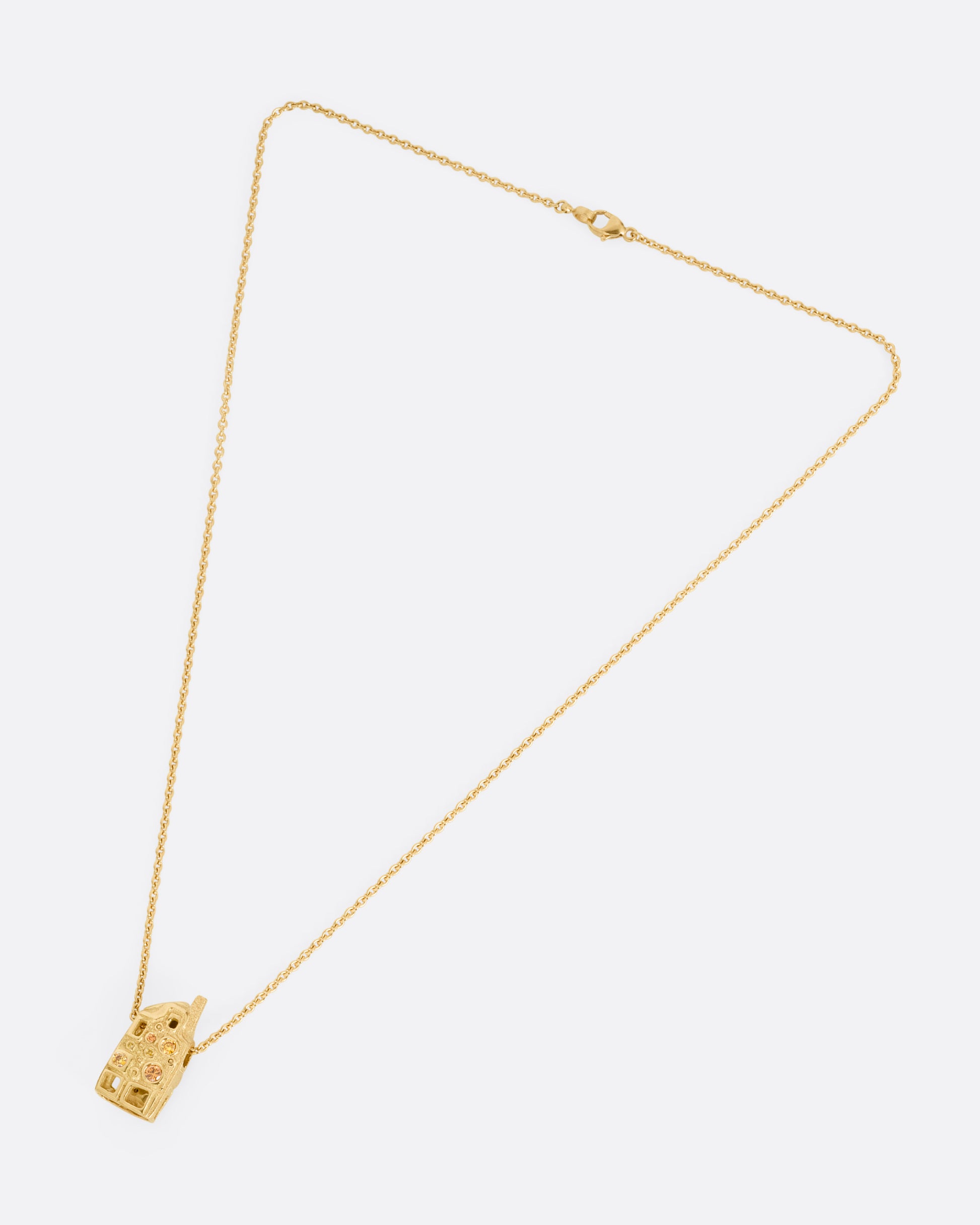 A yellow gold house-shaped pendant with multi-colored diamonds, on a cable chain, shown from the front. 