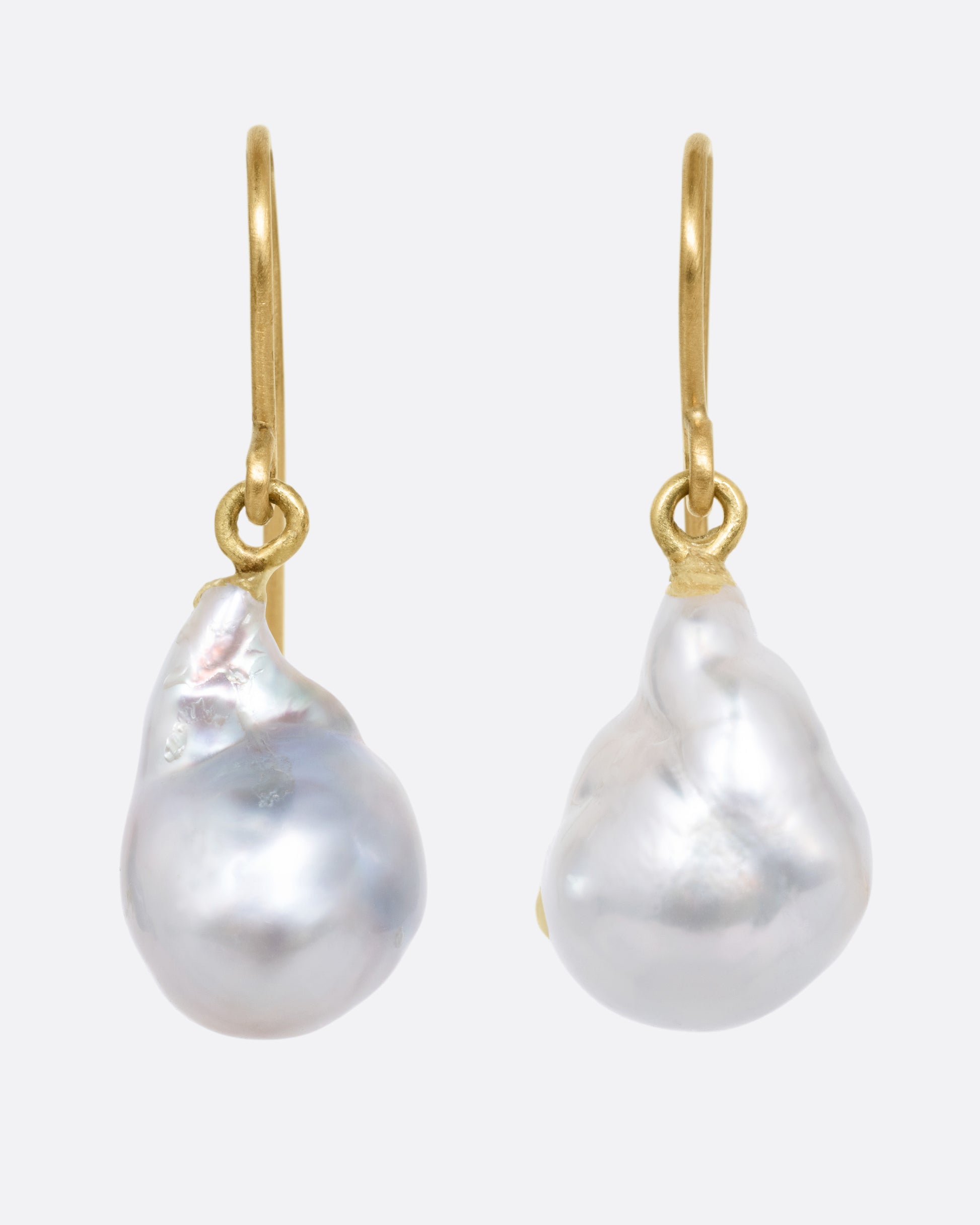 A pair of pearl earrings with yellow gold ear hooks, shown from the front.