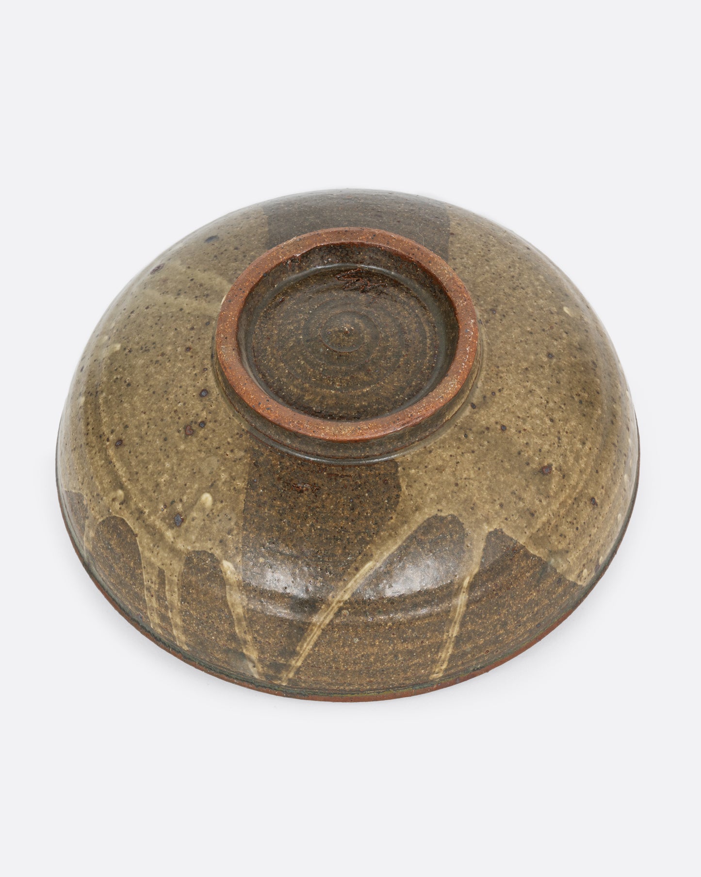 A ceramic serving bowl with a brown splattered glaze motif. Shown from the bottom.