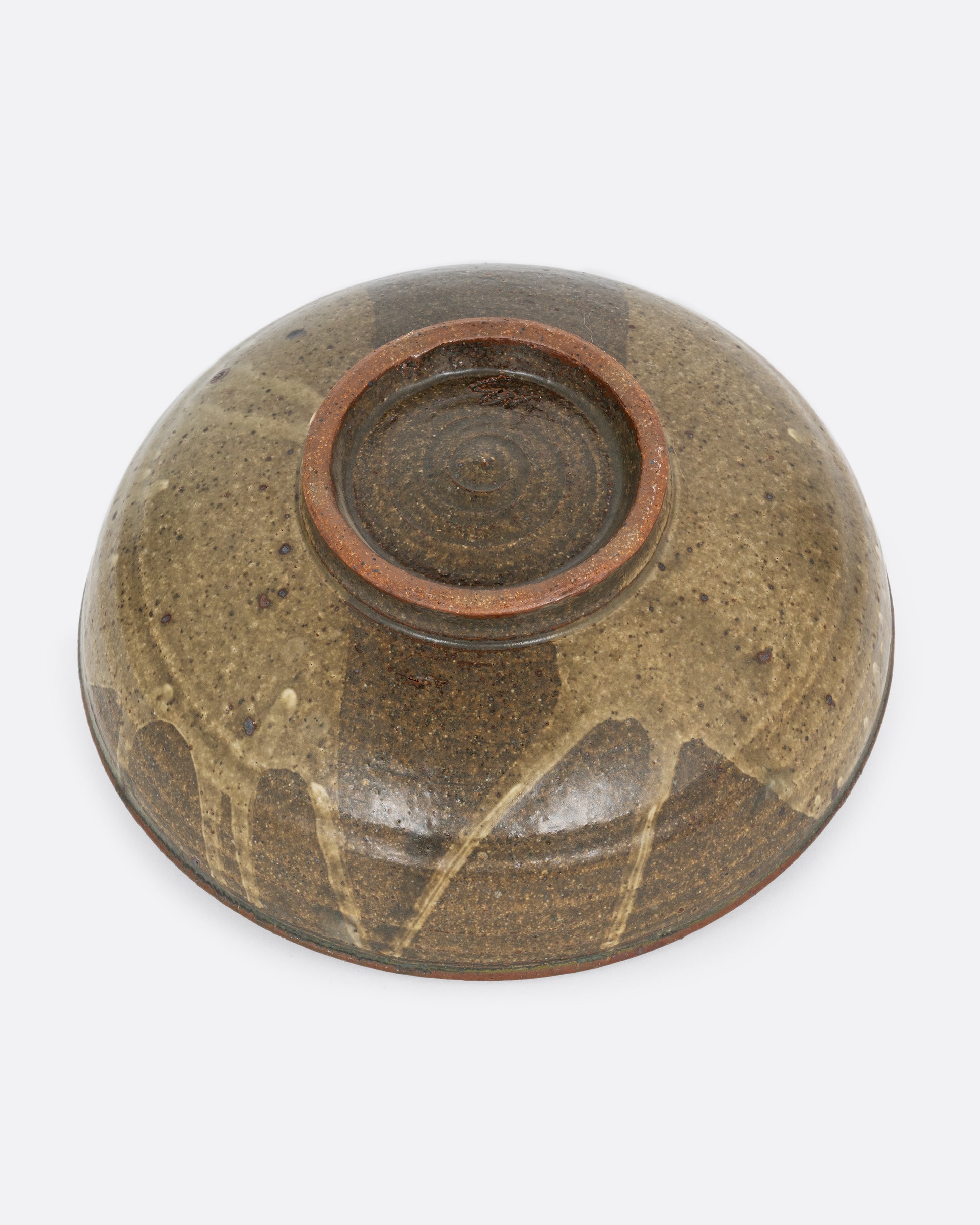 A ceramic serving bowl with a brown splattered glaze motif. Shown from the bottom.