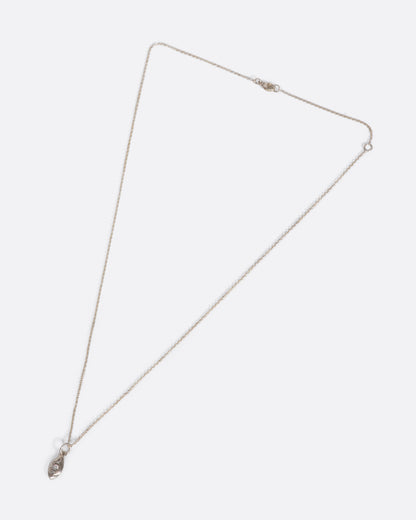 A silver cable chain necklace with a seed shaped pendant with three diamonds and oxidized etching. Shown closed lying flat from the front.