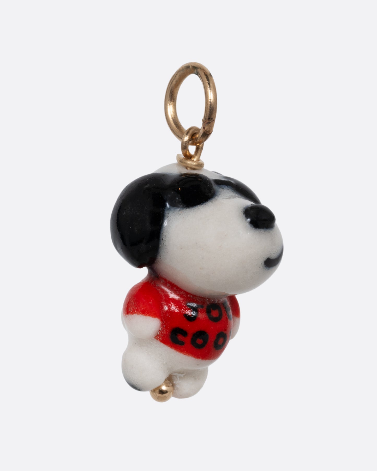 A "Joe Cool" porcelain Snoopy charm with a yellow gold bail. Shown from the side.