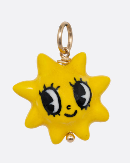 A yellow sun porcelain charm with a yellow gold bail. Shown from the front.