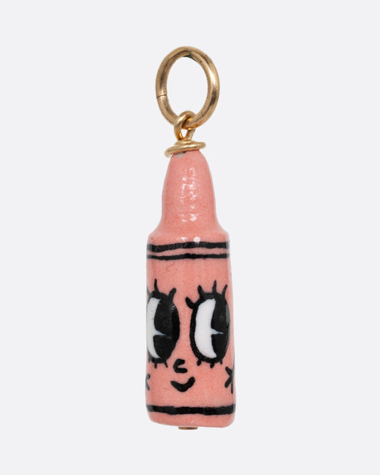 A pink crayon porcelain charm with a yellow gold bail. Shown from the front.