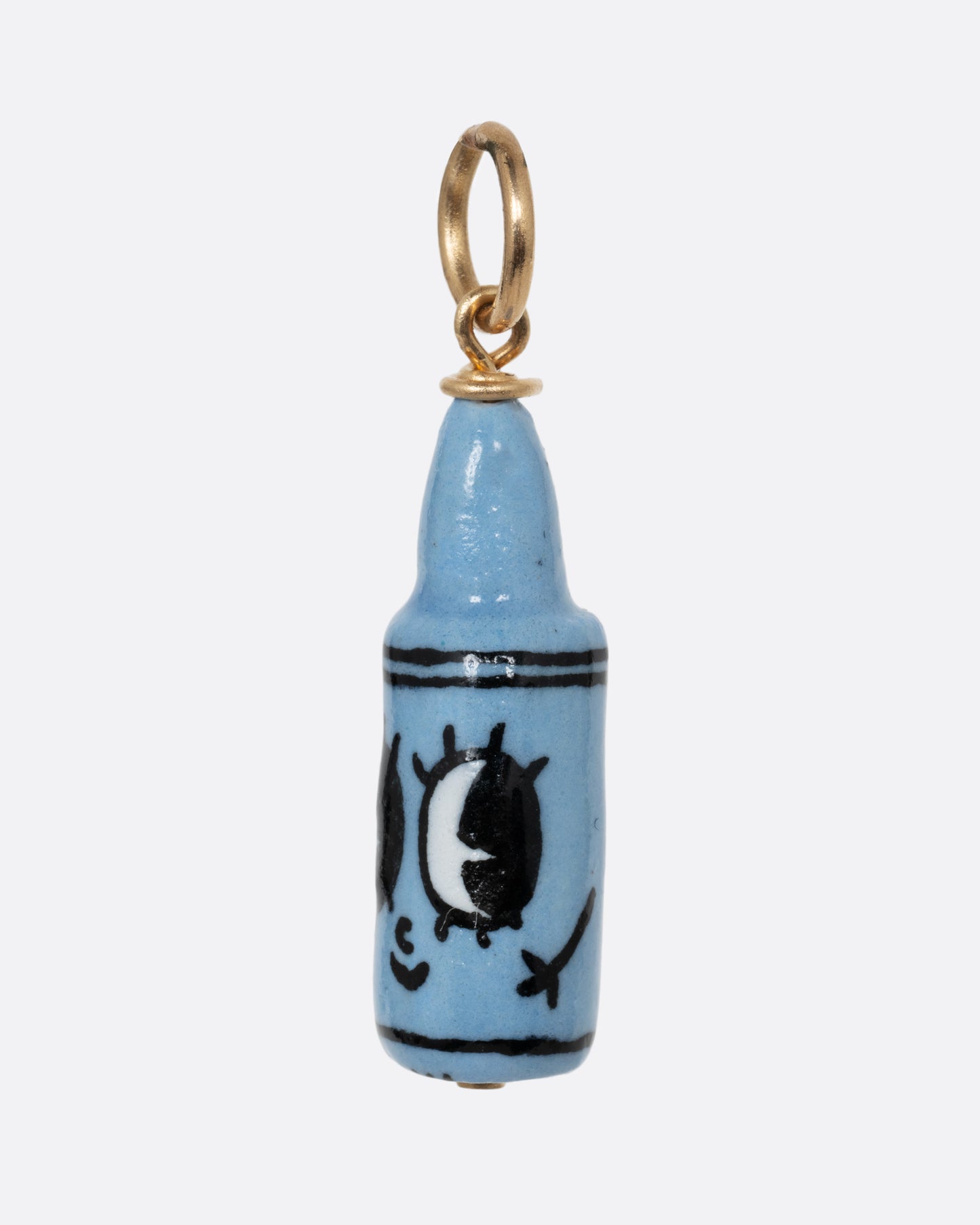 A blue crayon porcelain charm with a yellow gold bail. Shown from the side.