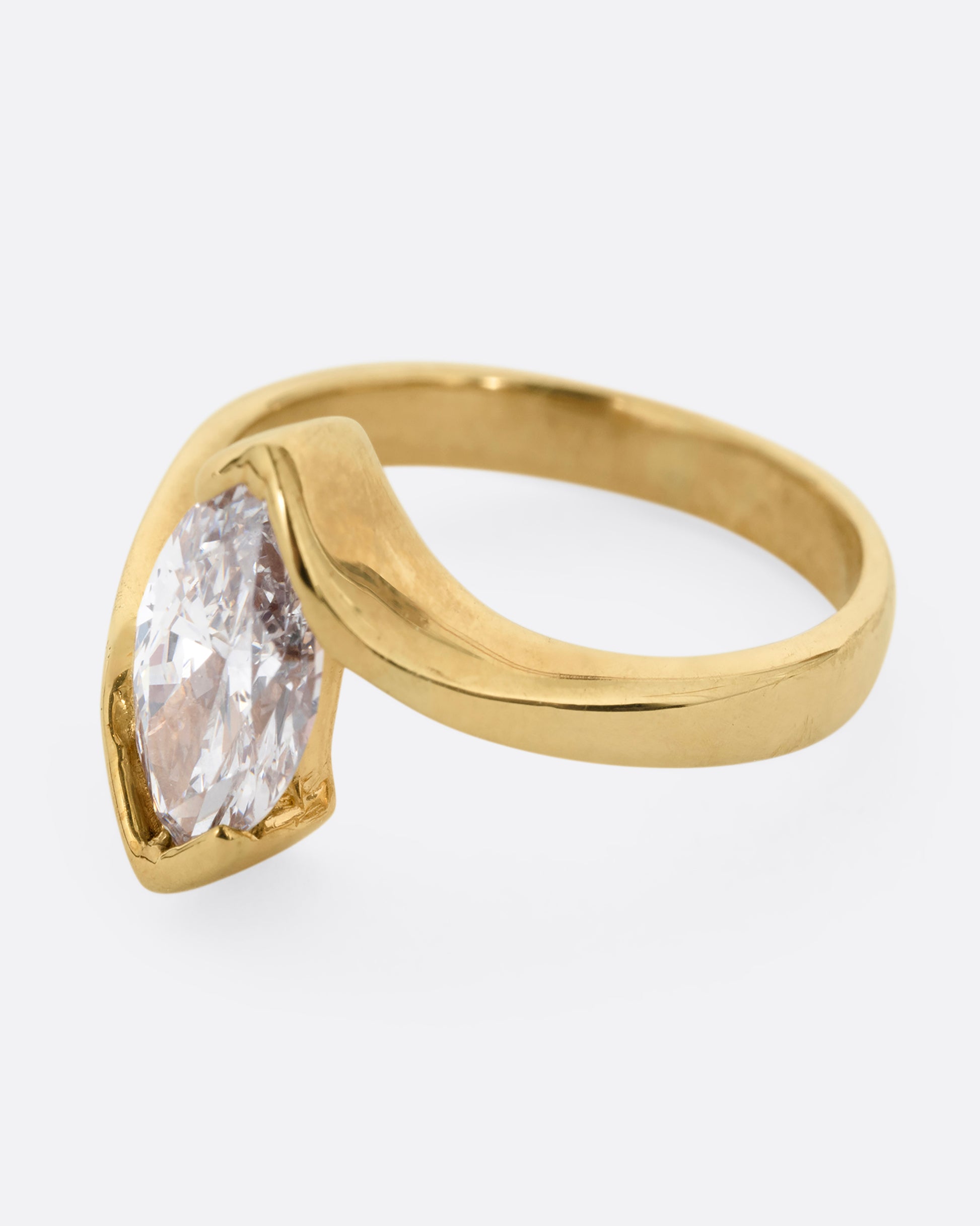 A yellow gold ring with a marquis diamond at the center. Shown from the side.
