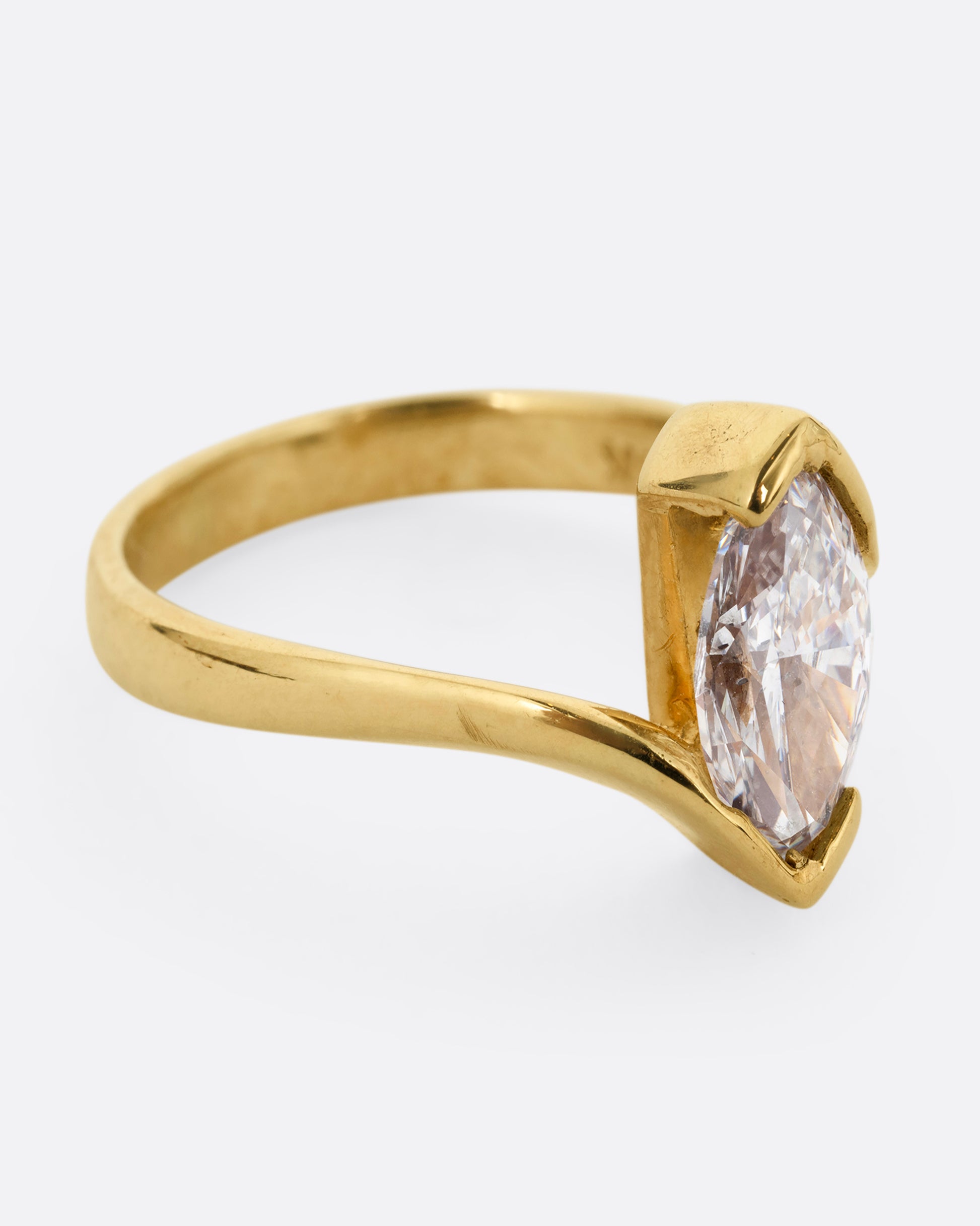 A yellow gold ring with a marquis diamond at the center. Shown from the side.