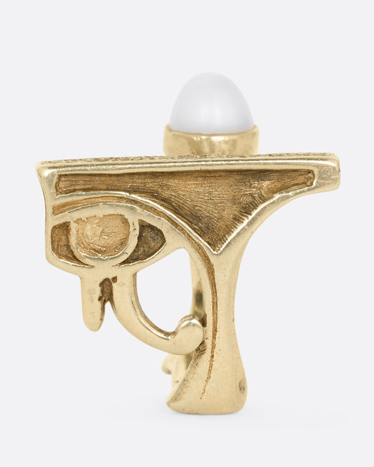 A yellow gold ring with the eye of Horus and a bezel set moonstone on the top. Shown from the side.
