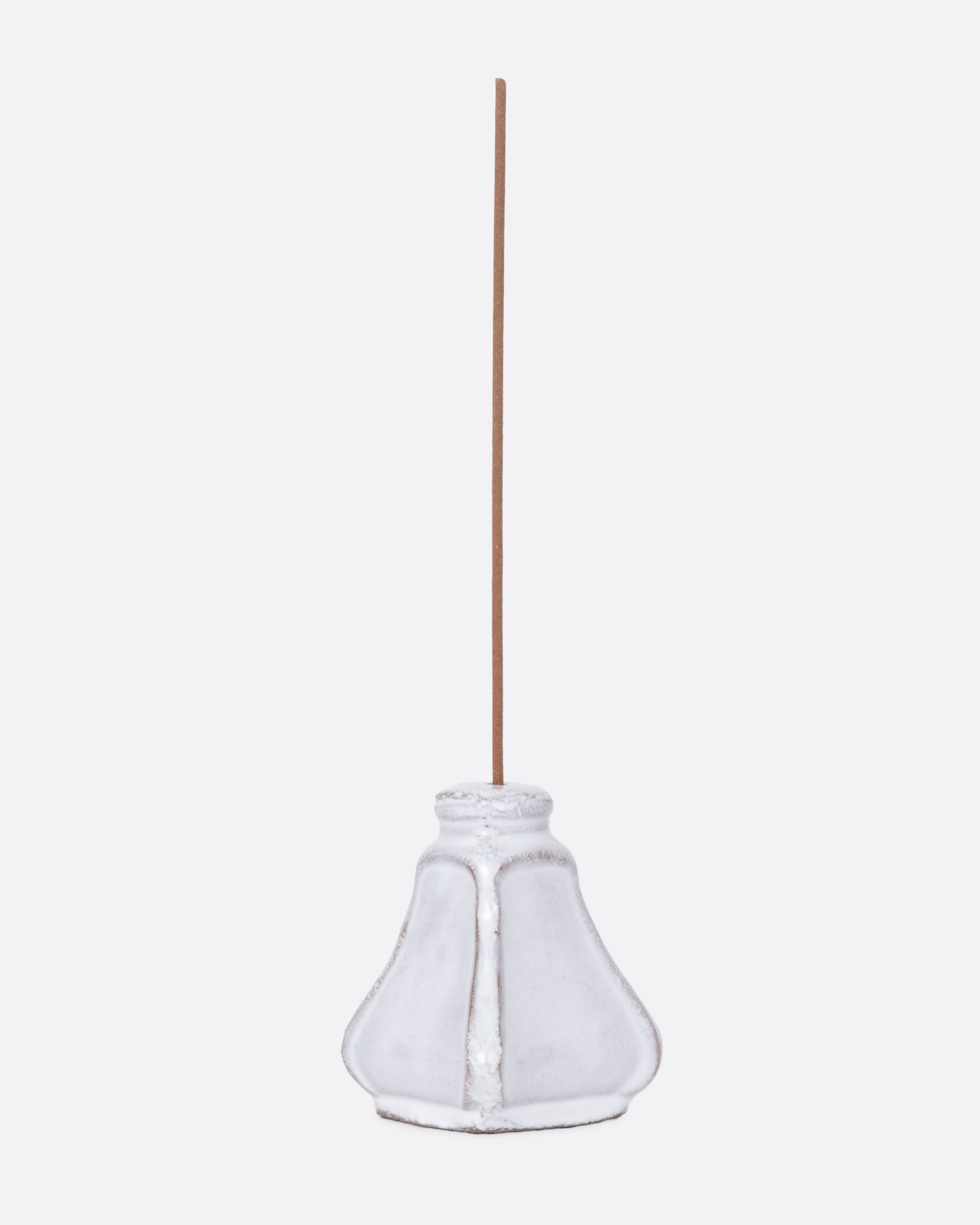 A white ceramic salt and pepper shaped incense burner with a stick in it, shown from the side.
