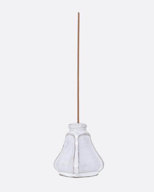 A white ceramic salt and pepper shaped incense burner with a stick in it, shown from the side.