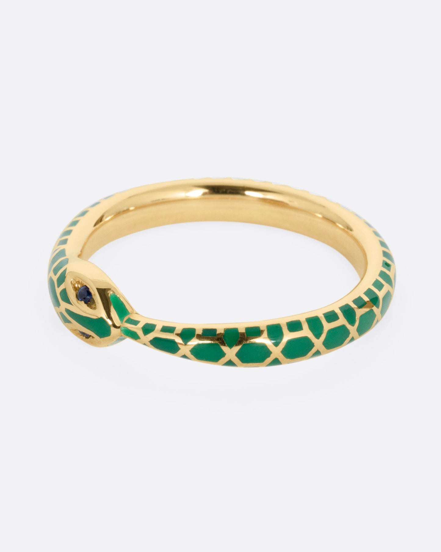 A yellow gold  ouroboros ring with sapphire eyes and a green enamel snake skin pattern, shown from the front.