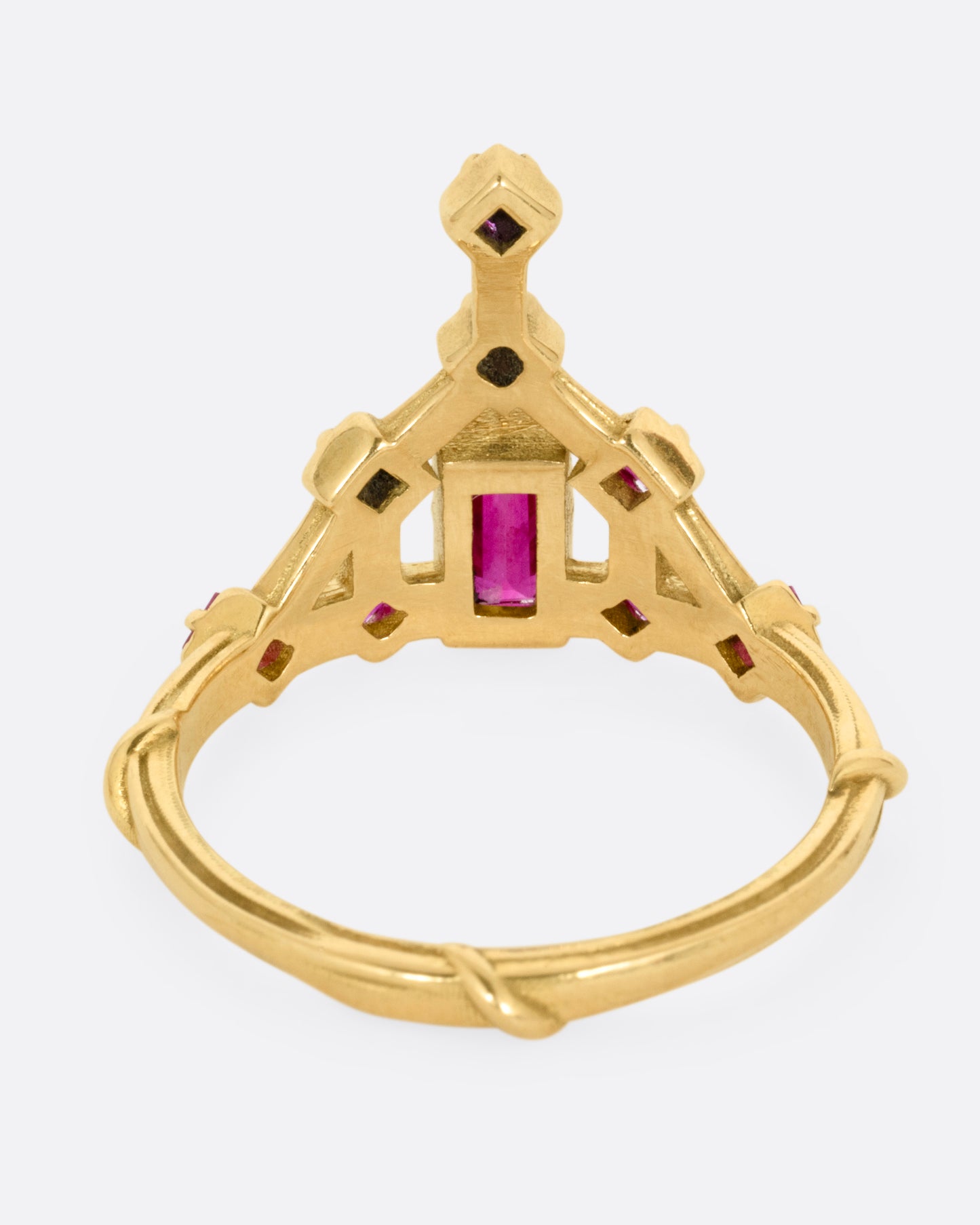 A yellow gold ring with a baguette ruby and princess cut ruby accent. Shown from the back.