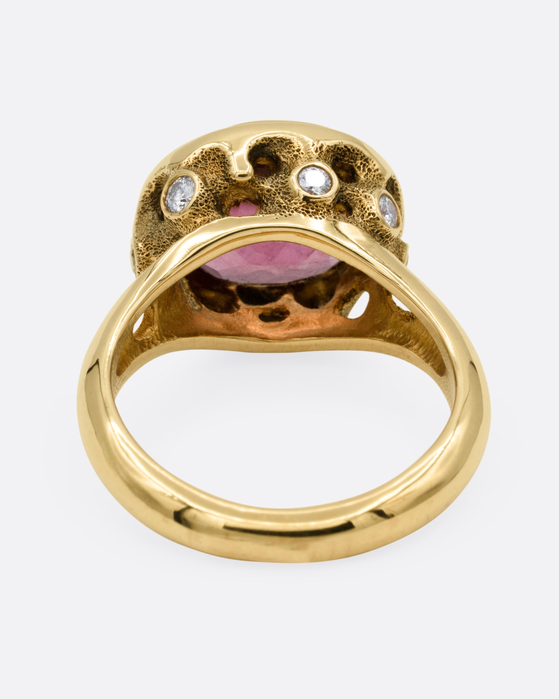 A yellow gold ring with a pink tourmaline and diamond accents. Shown from the back.