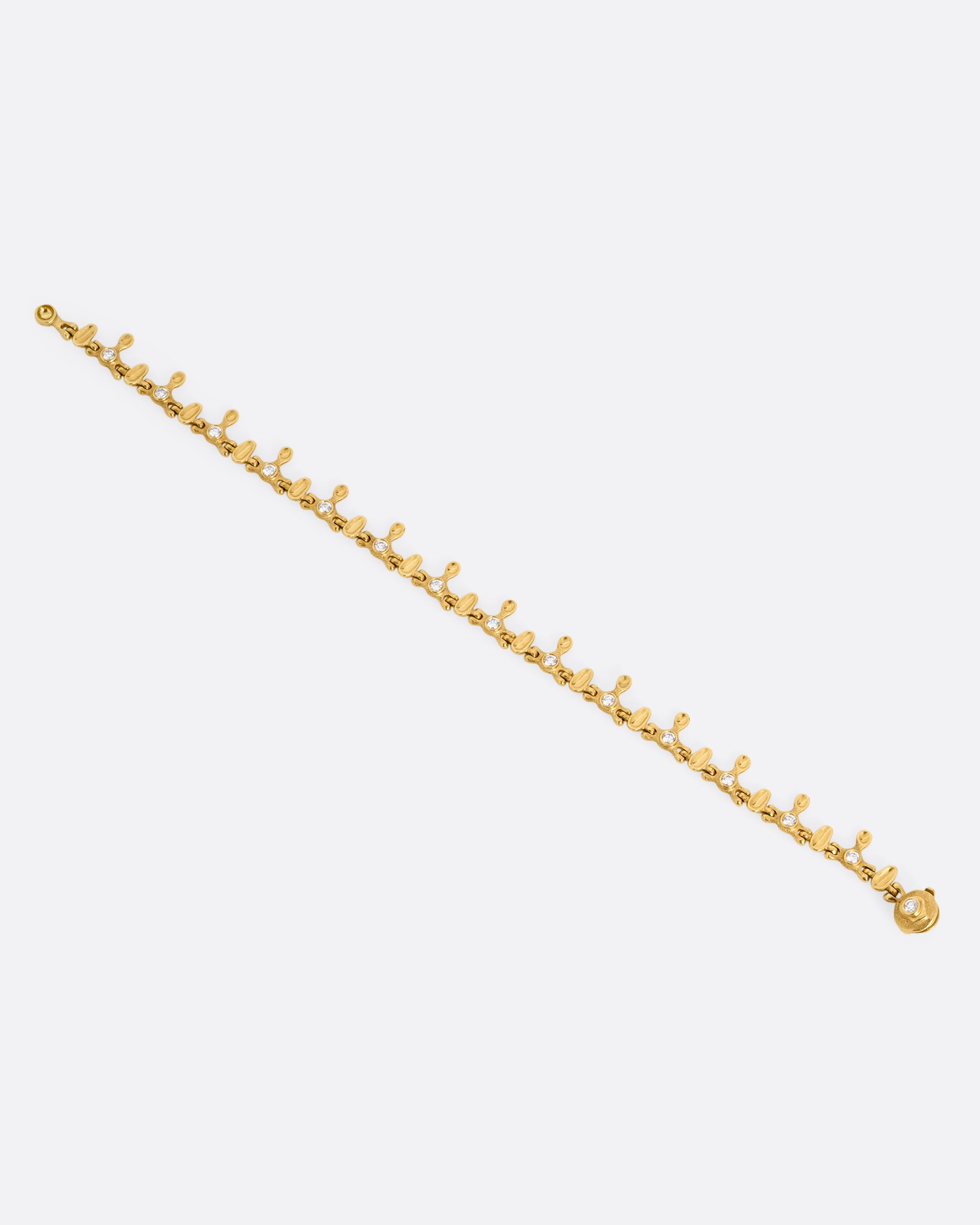 A yellow gold bracelet with a drippy pattern and white diamonds, shown from the front.