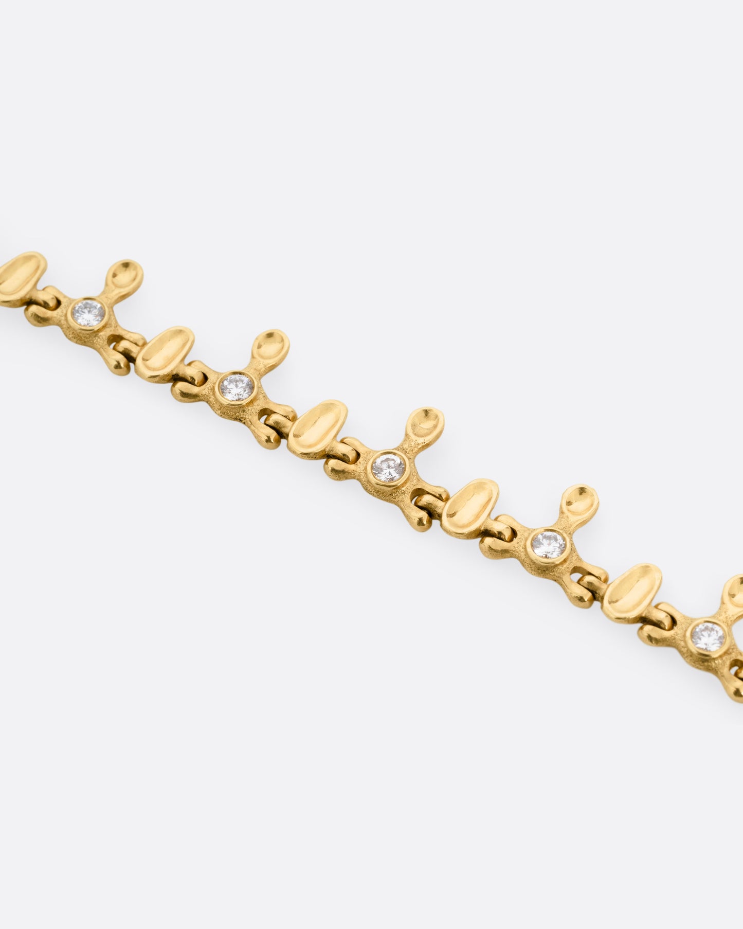 A yellow gold bracelet with a drippy pattern and white diamonds, shown from the front.