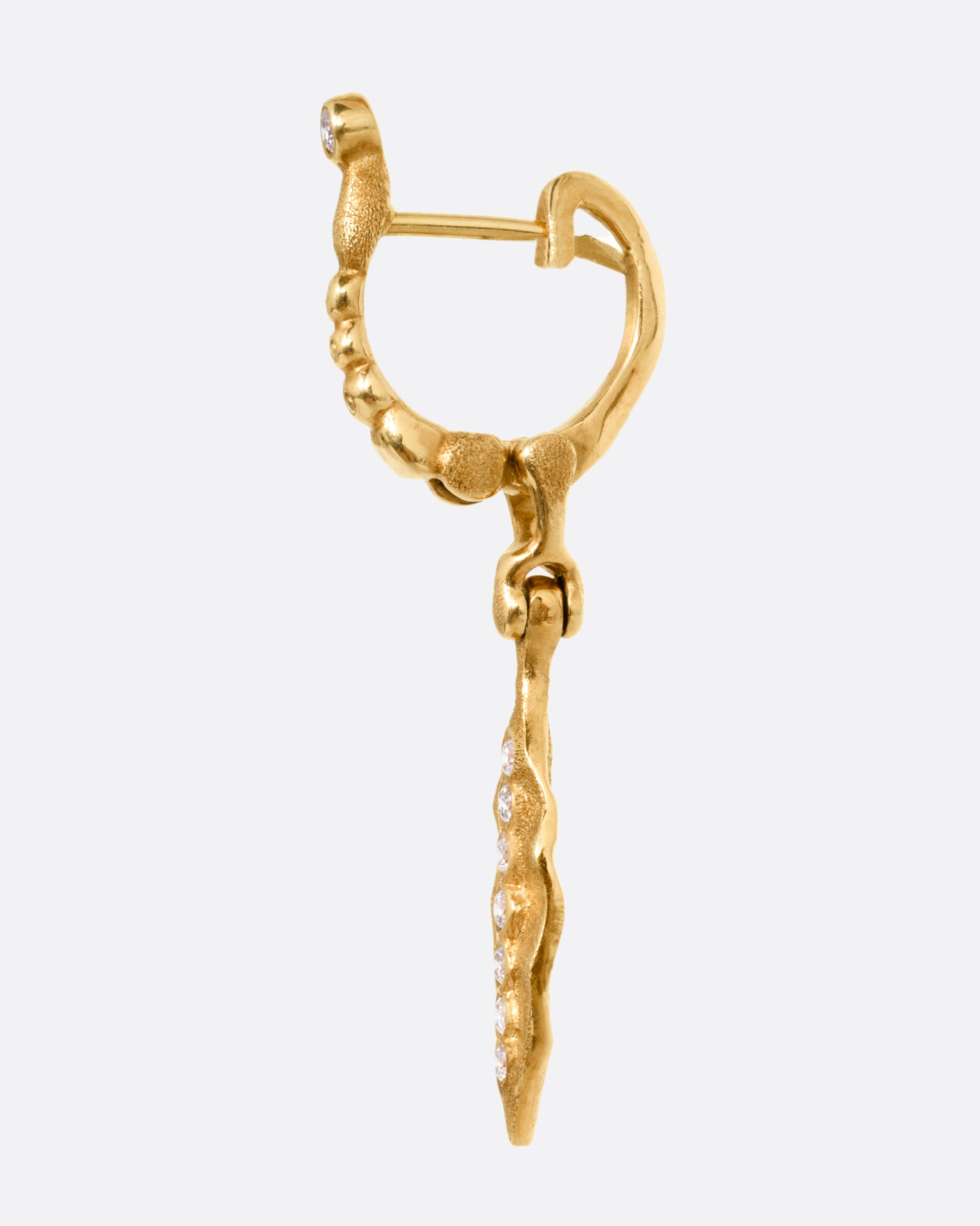 A  gold drop earring with a dangling leaf and diamond accents, shown from the side.