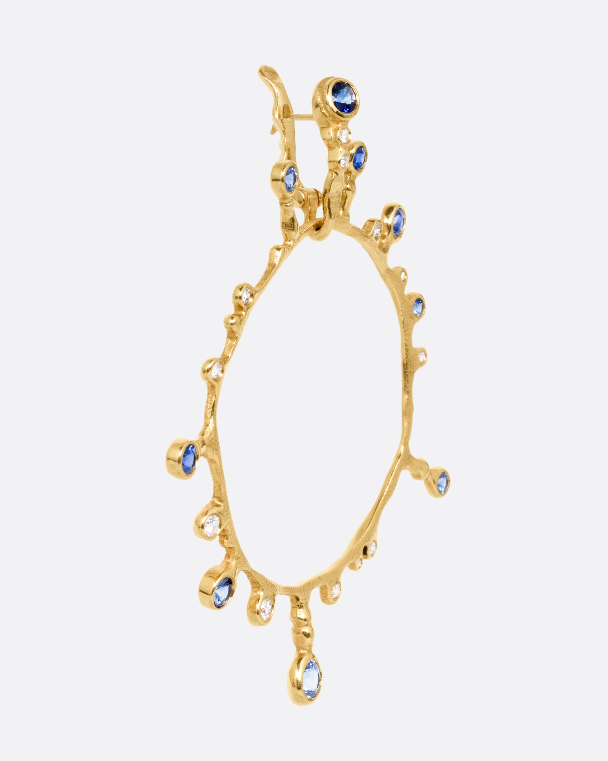 A yellow gold hoop sunburst earring with diamonds and sapphires. Shown from the side.