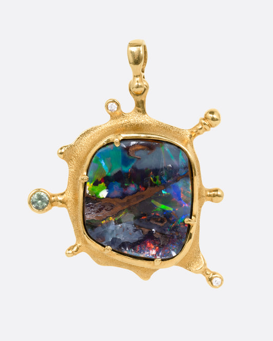 A yellow gold pendant with a boulder opal and diamonds and sapphires along its edges, shown from the front.