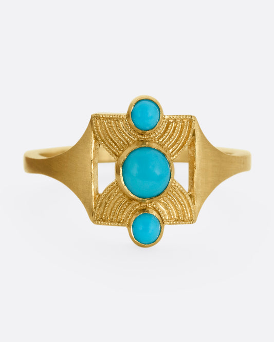A yellow gold hourglass shaped ring with three stacked bezel set turquoises. Shown from the front.