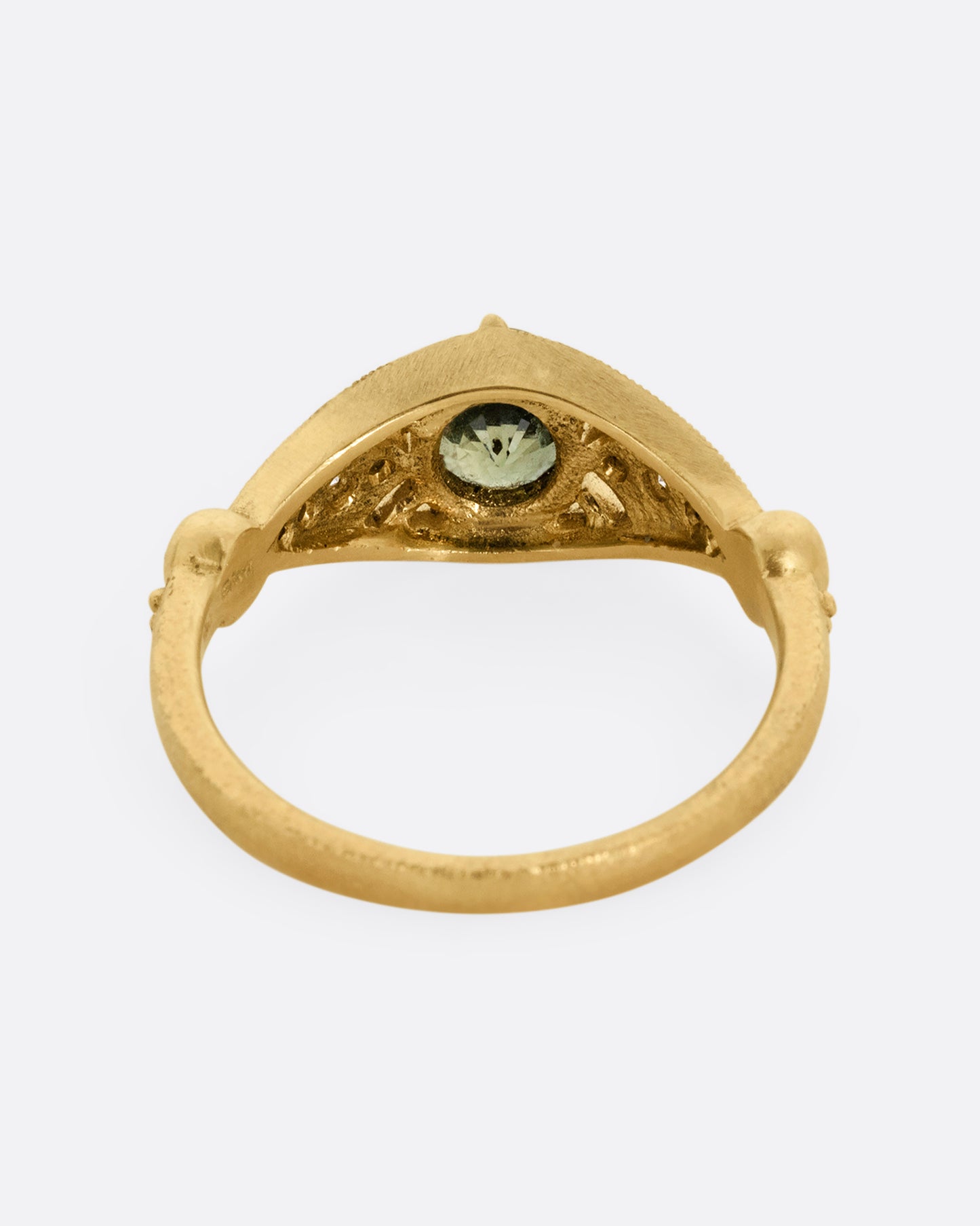 A yellow gold ring with a green Montana sapphire at the center and cutout details and white diamonds. Shown from the back.