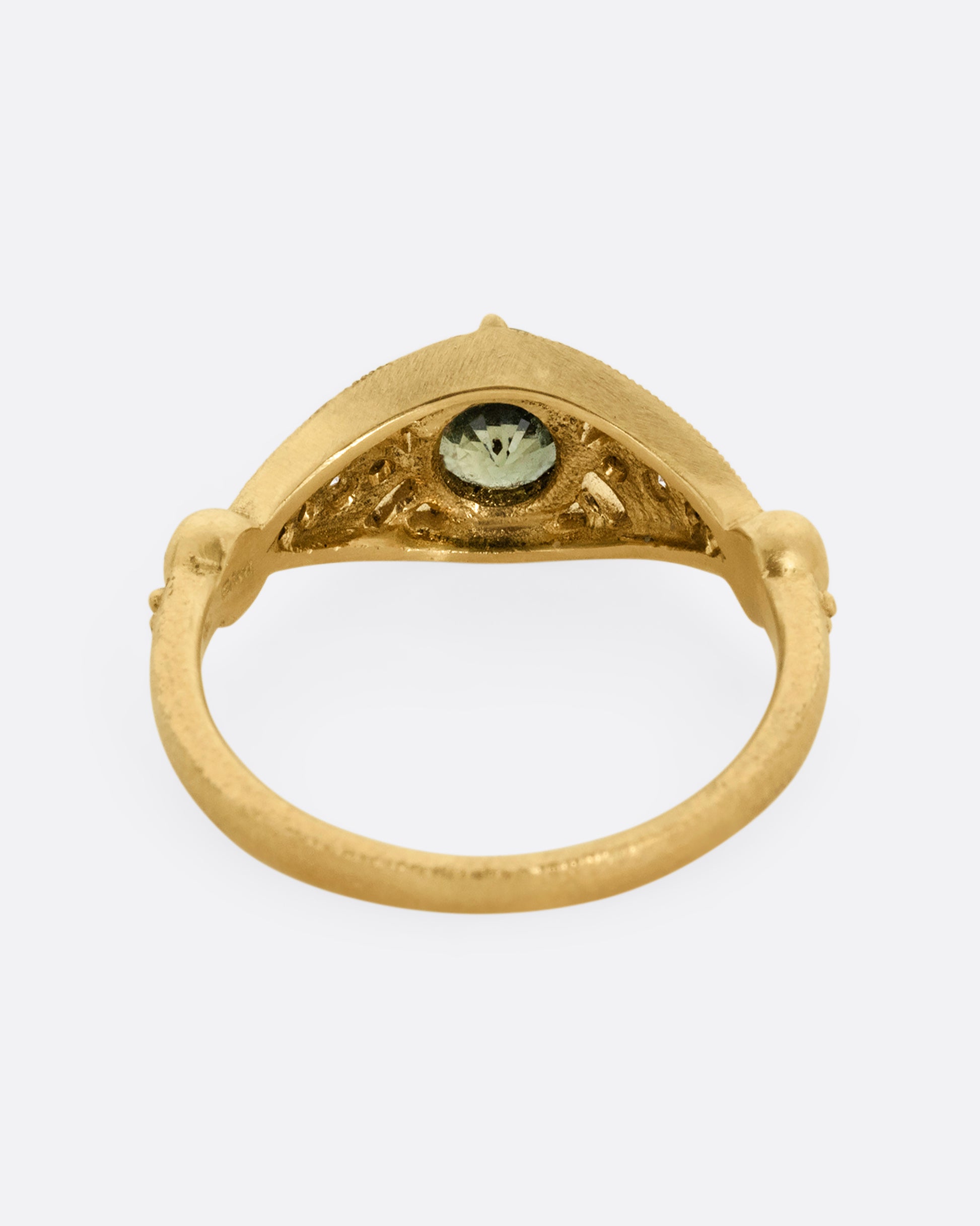 A yellow gold ring with a green Montana sapphire at the center and cutout details and white diamonds. Shown from the back.
