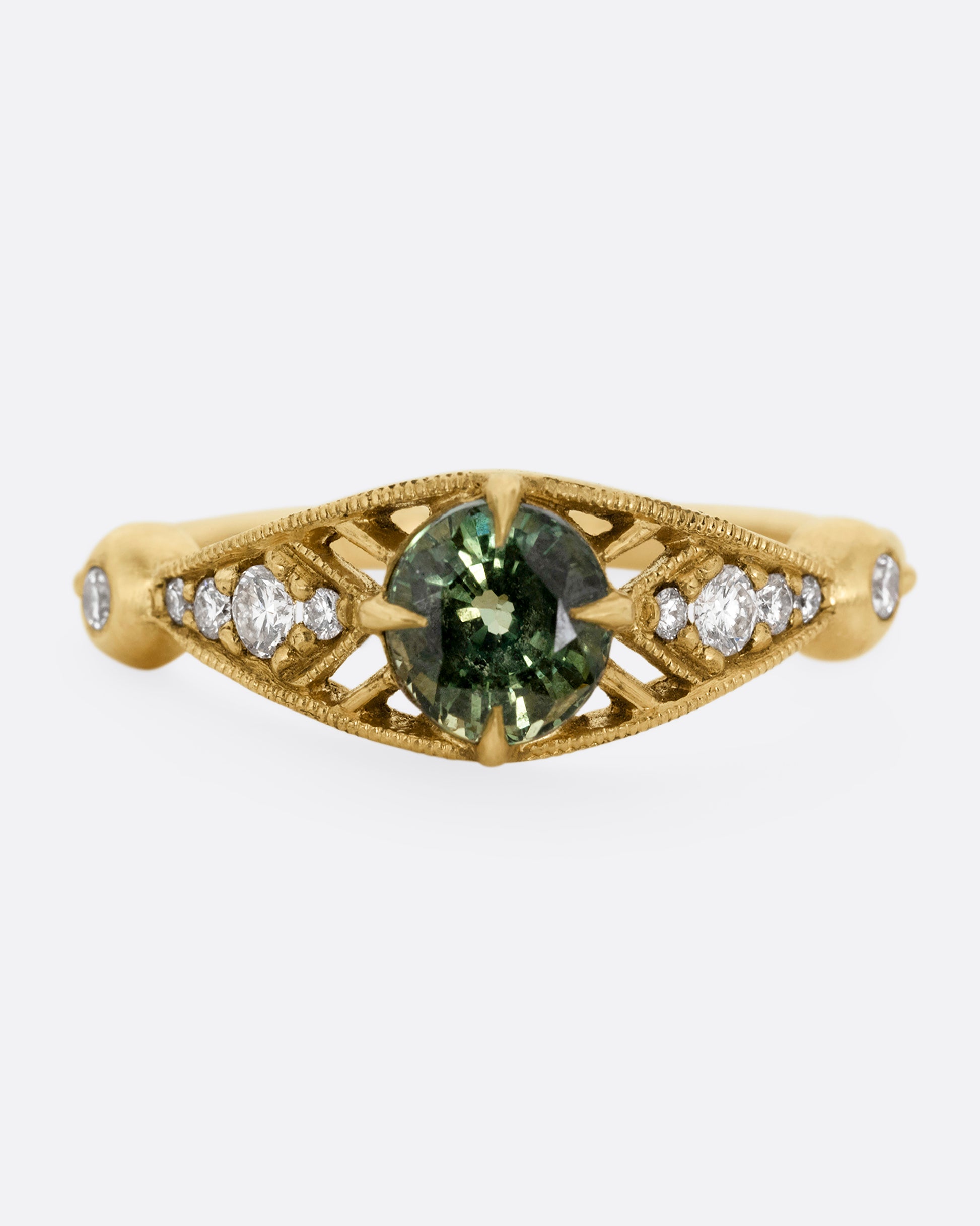 A yellow gold ring with a green Montana sapphire at the center and cutout details and white diamonds. Shown from the front.