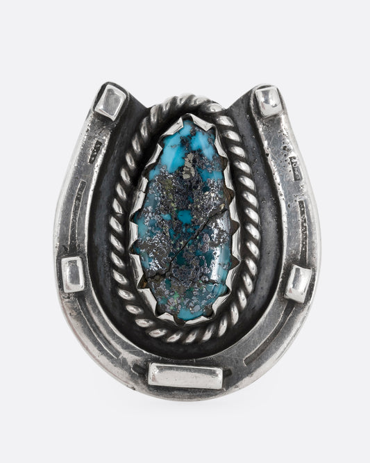 A silver horseshoe ring with a free- form turquoise in the center. Shown from the front.
