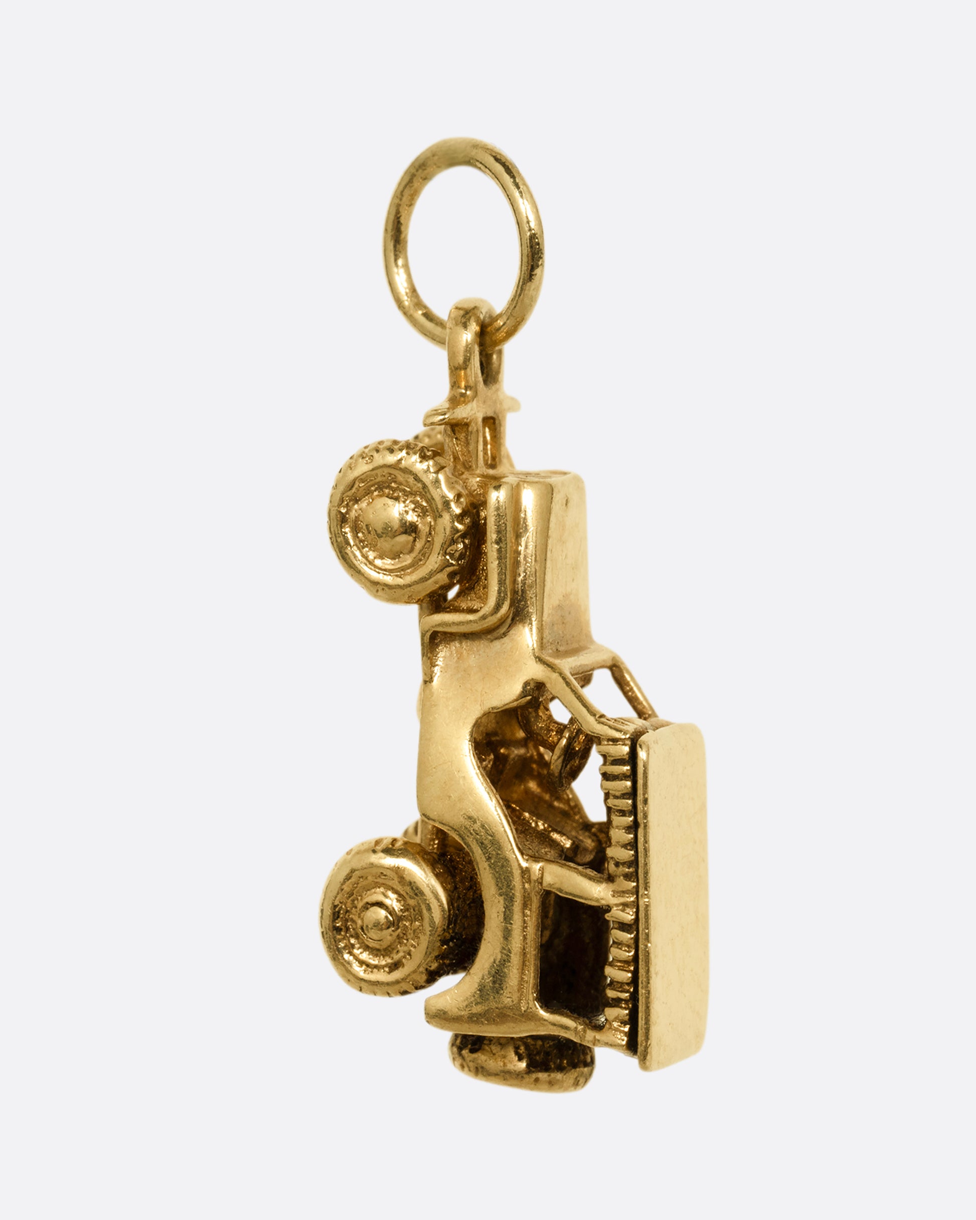 A yellow gold jeep charm. Shown from the side.