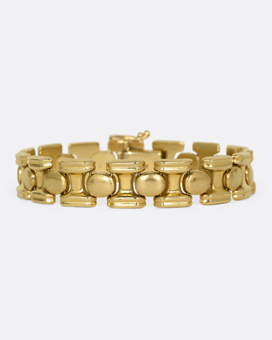 A yellow gold bracelet with repeating oval sections. Shown from the front.