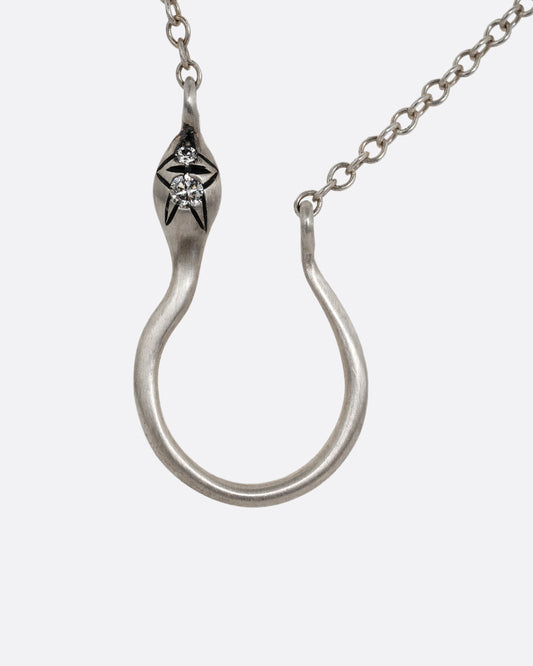 A silver snake shaped charm holder with diamonds on its face, hanging from a cable chain. Shown from the front.