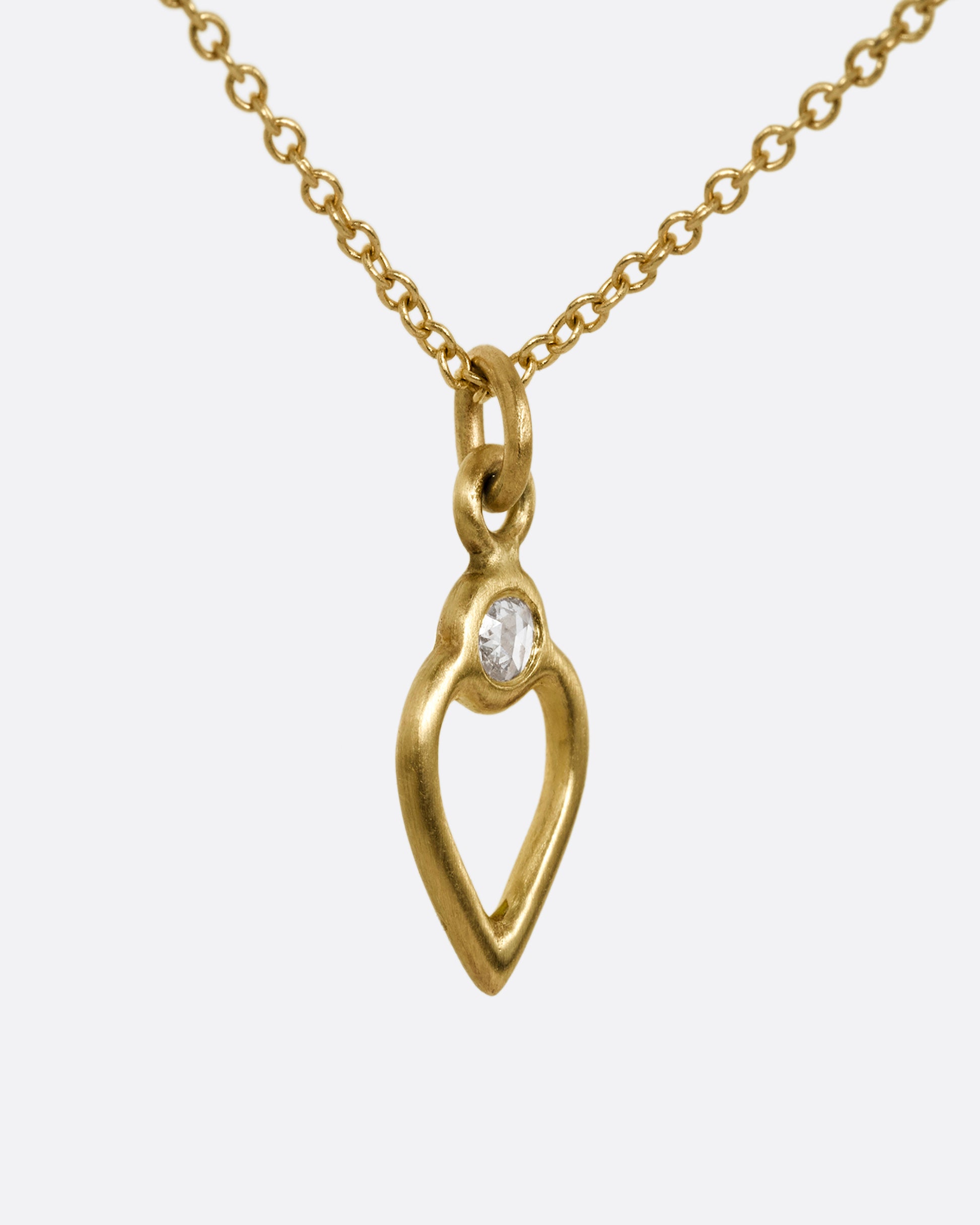 A yellow gold necklace with an open heart pendant with a diamond. Shown from the side.