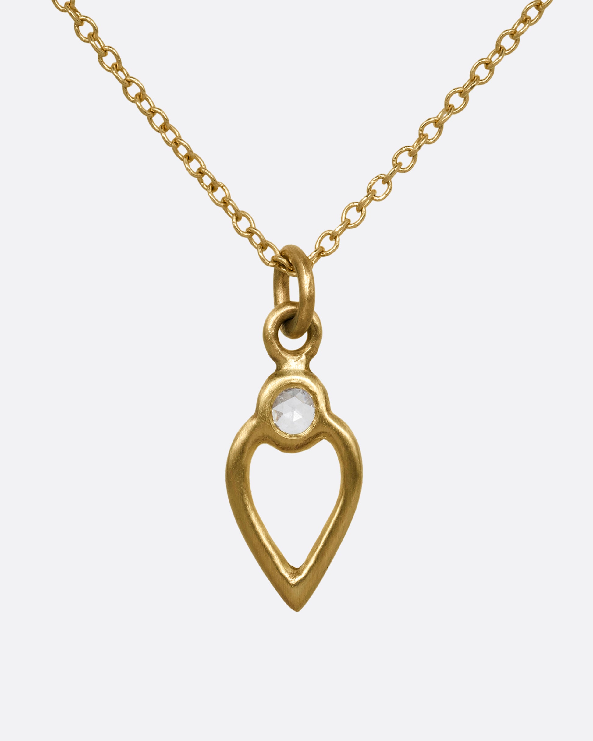 A yellow gold necklace with an open heart pendant with a diamond. Shown from the front.