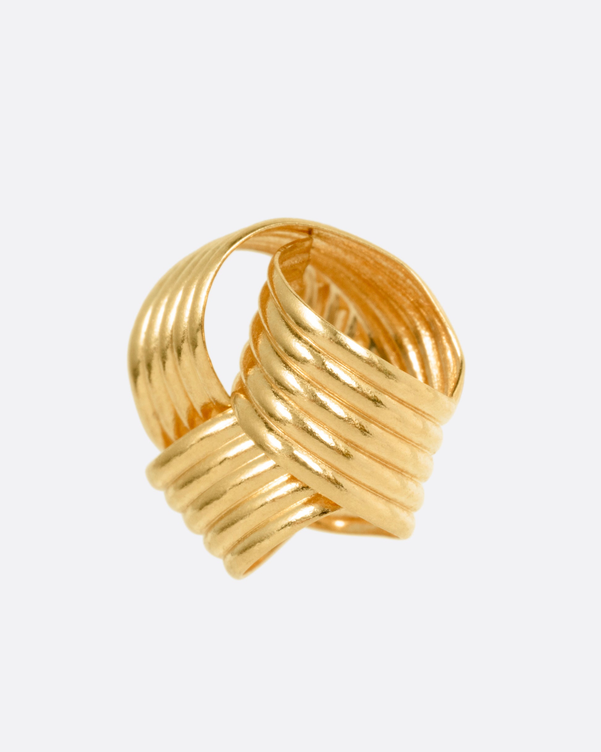 A knot shaped yellow gold stud earring, shown from the side.