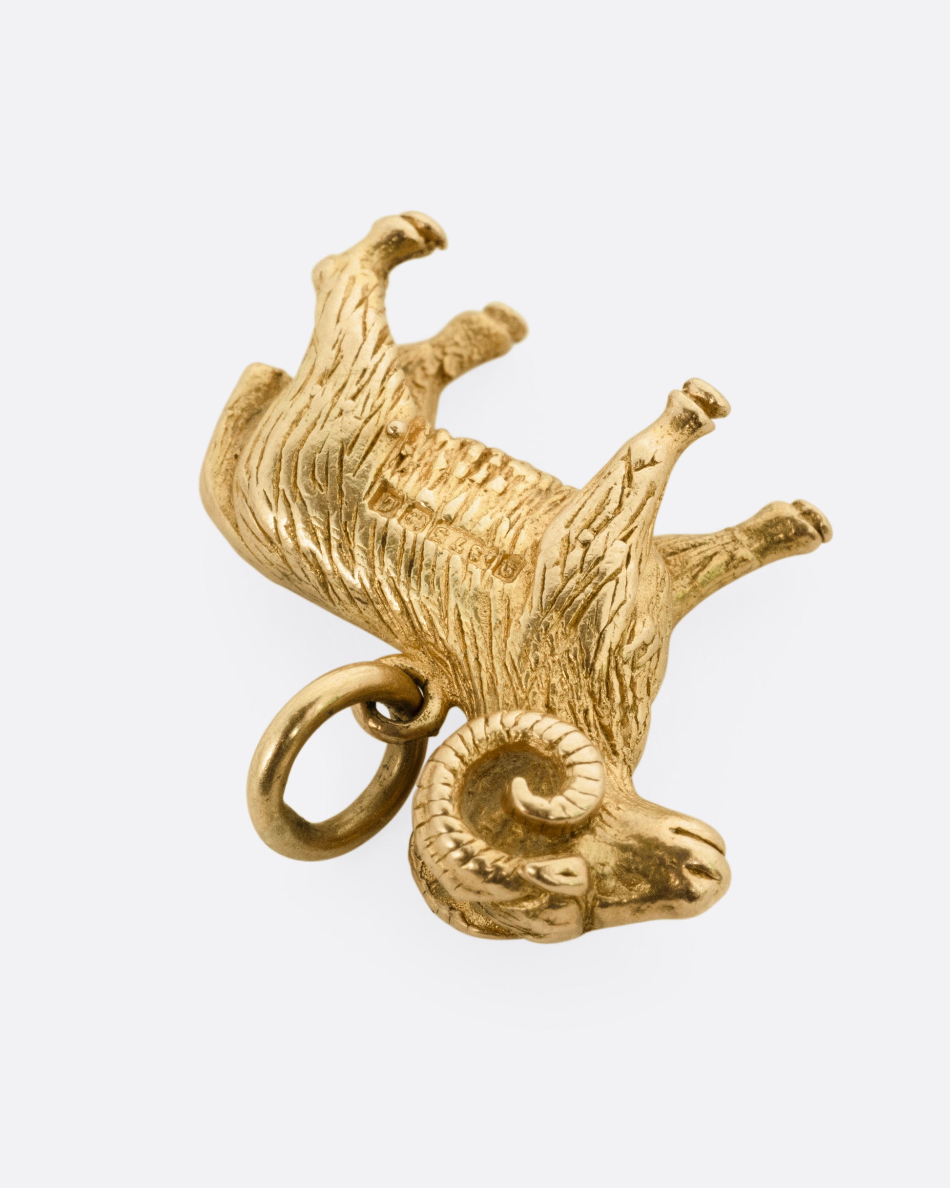 A yellow gold goat pendant, shown from the side.