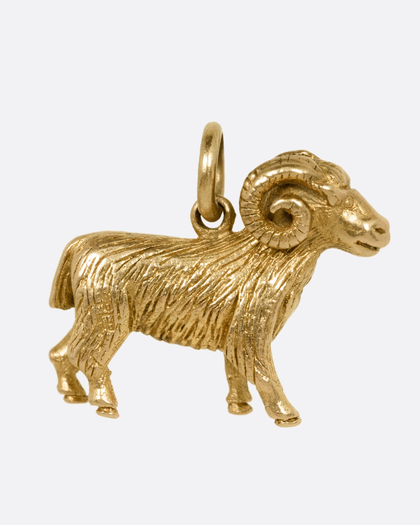 A yellow gold goat pendant, shown from the side.