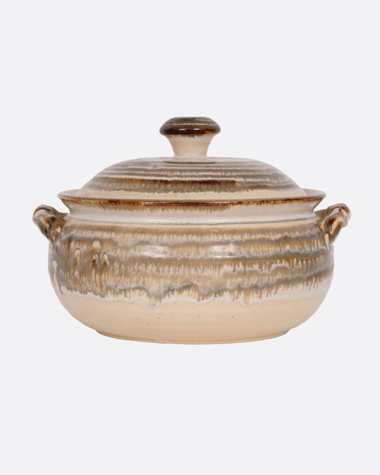 A beige striped casserole dish with dual handles and a domed lid, shown from the front.