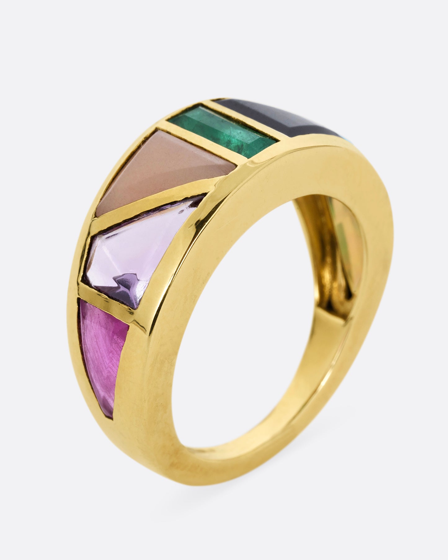 A yellow gold band with an array of gemstones in angular shapes. Shown standing up from the side.