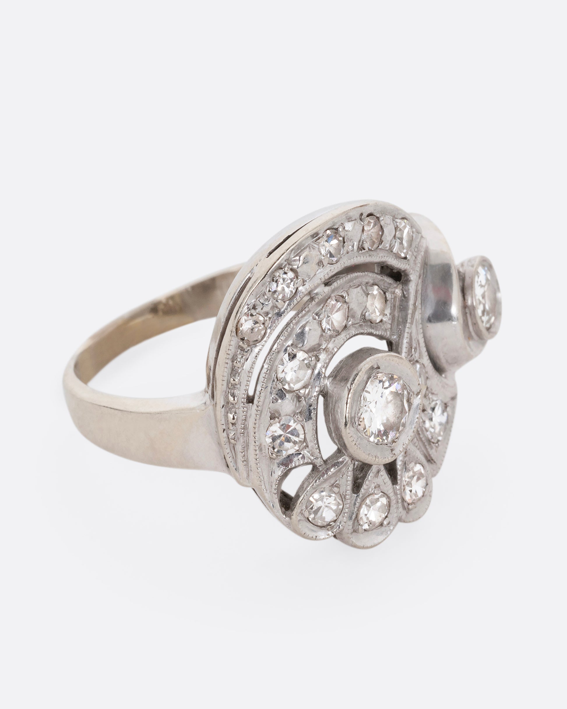 A white gold curving ring with diamonds. Shown from the side.