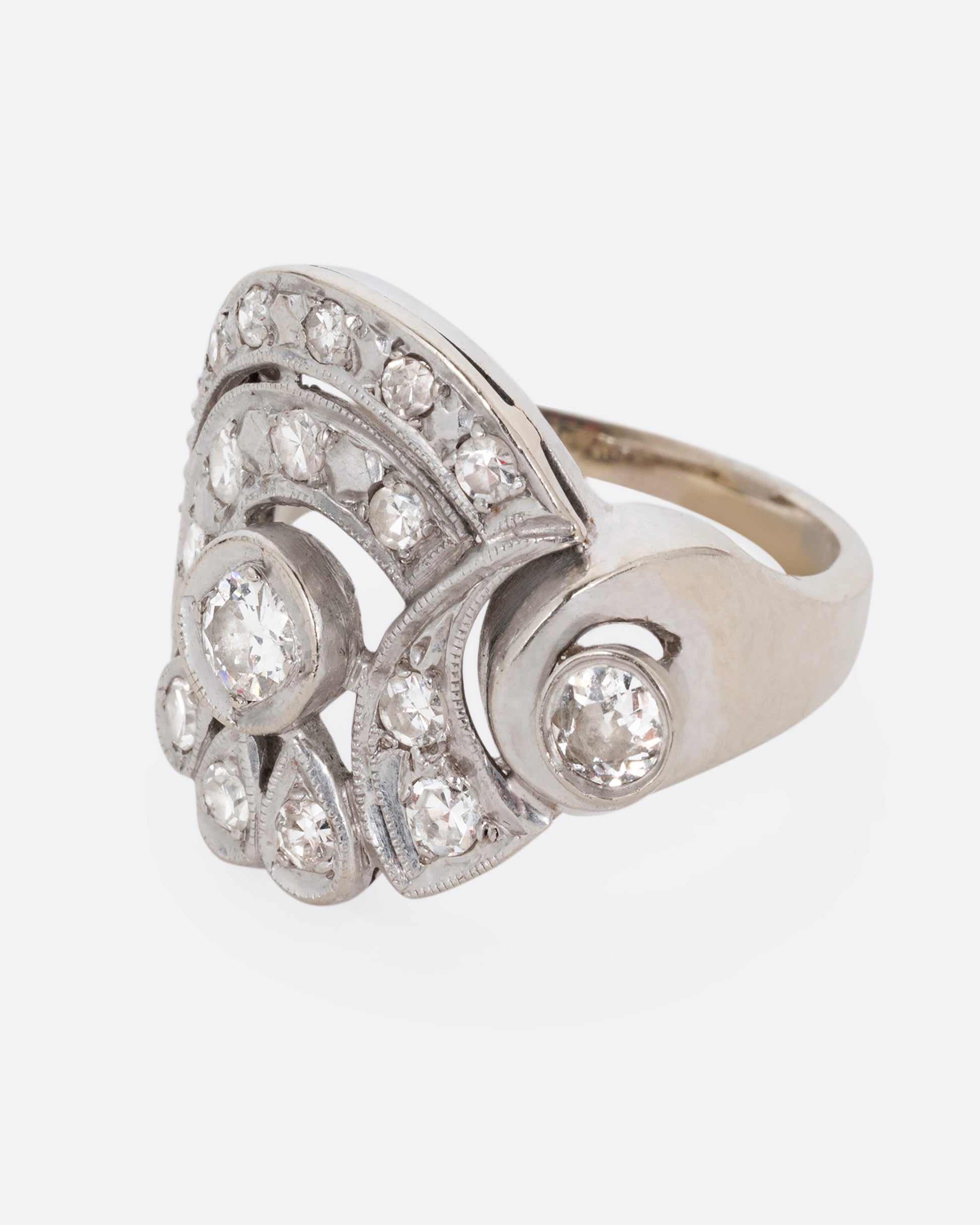 A white gold curving ring with diamonds. Shown from the side.