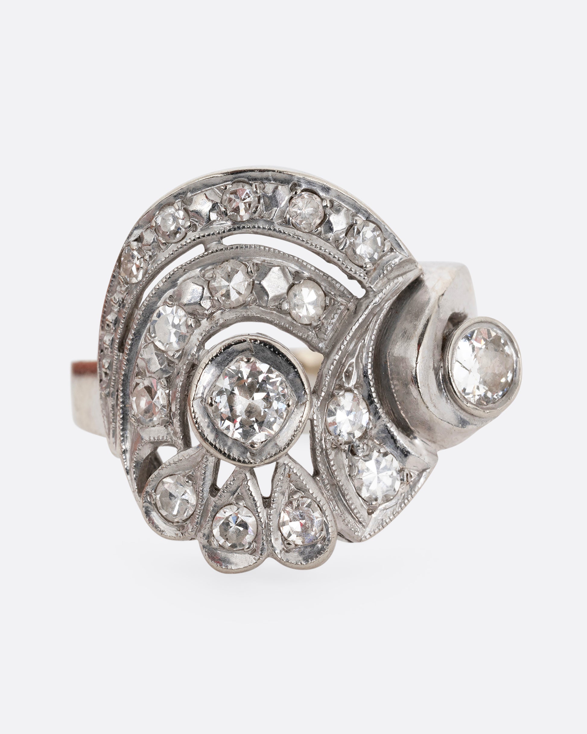 A white gold curving ring with diamonds. Shown from the front.