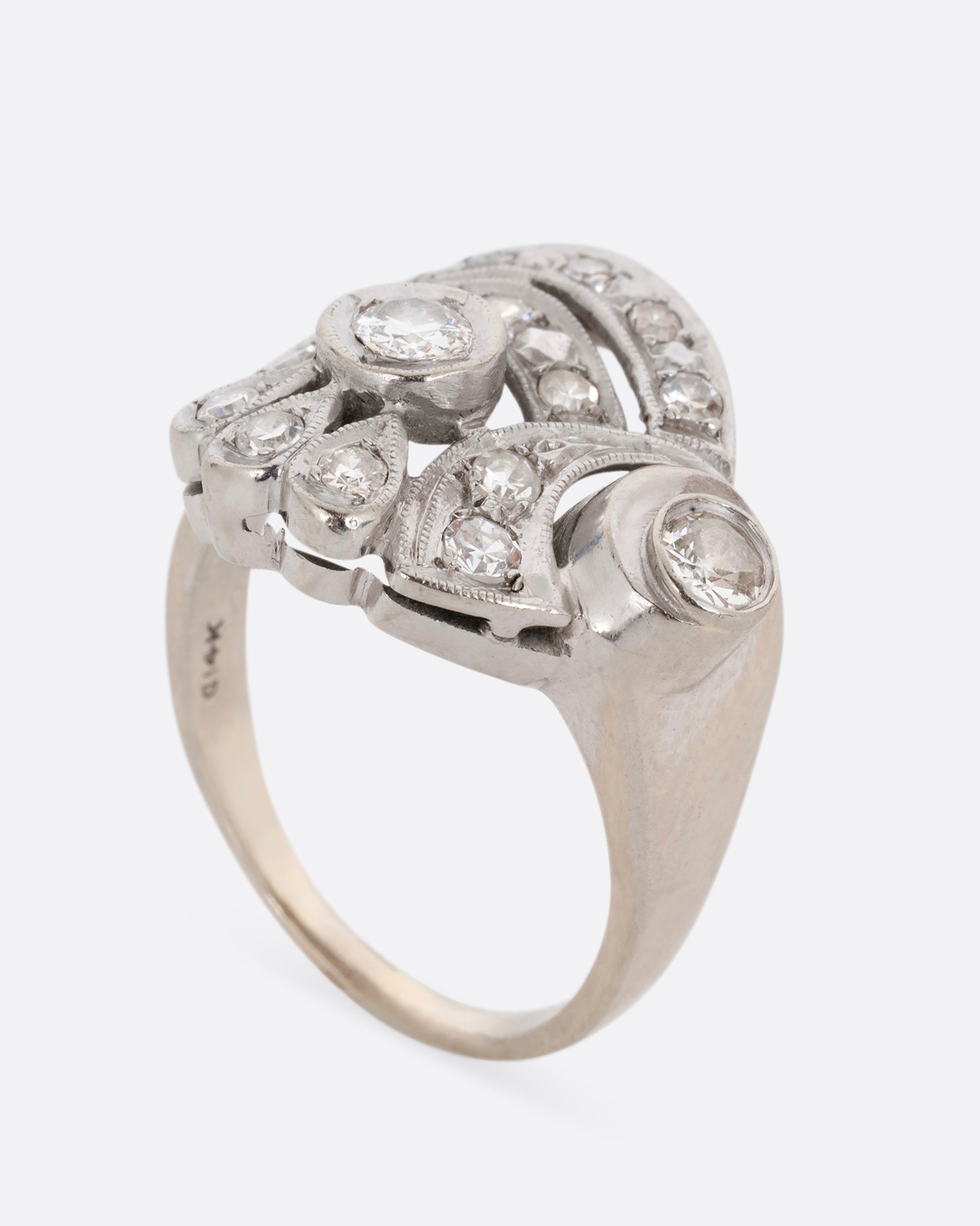 A white gold curving ring with diamonds. Shown standing up from the side.