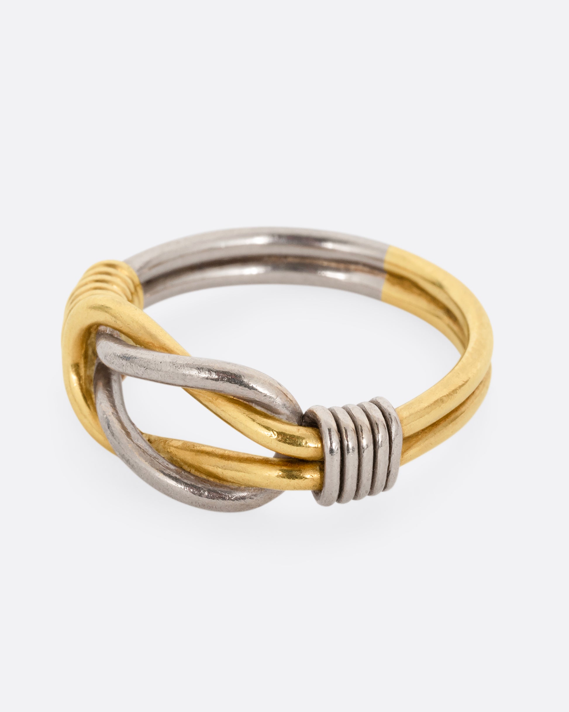 A white and yellow gold infinity knot ring. Shown from the side.