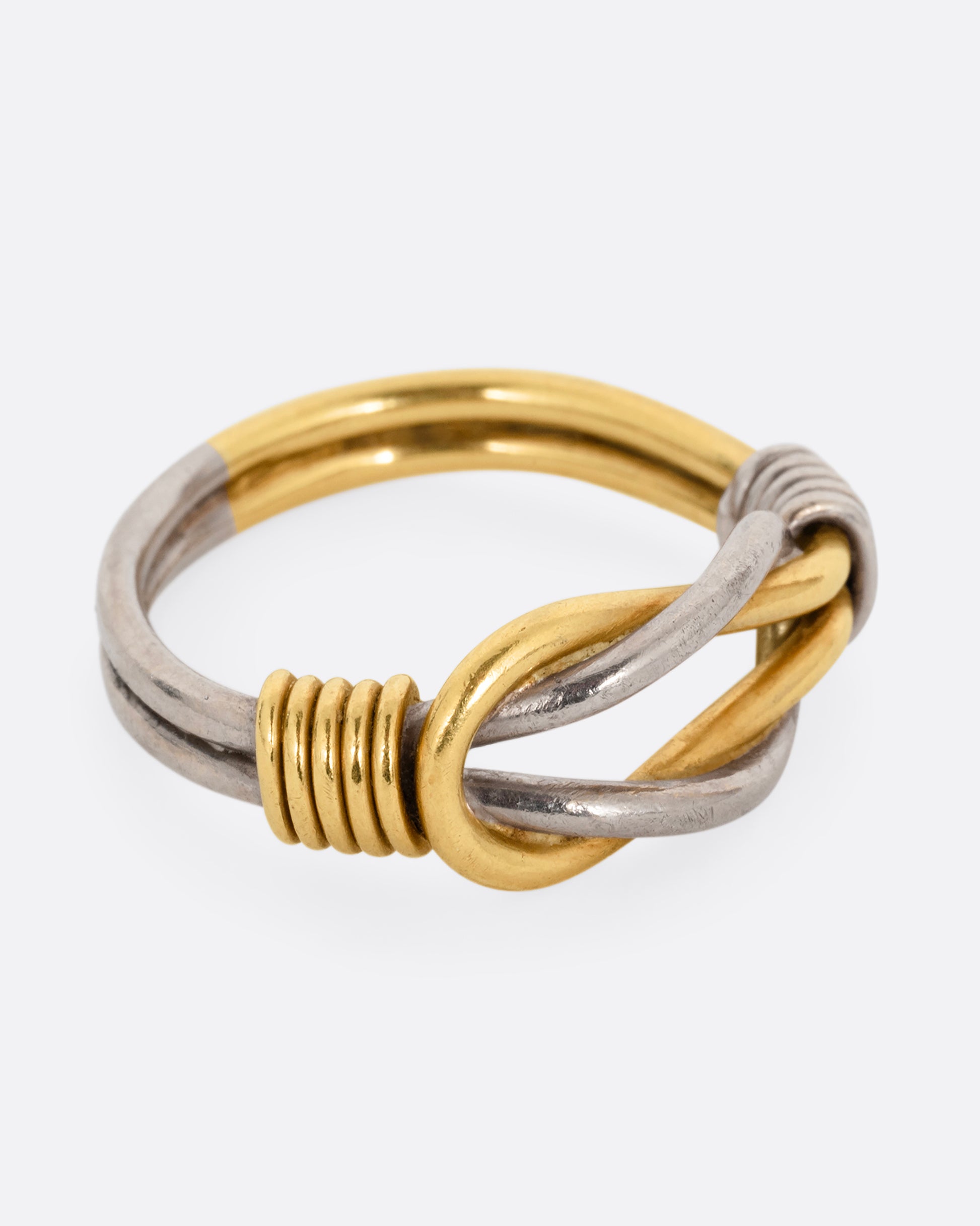 A white and yellow gold infinity knot ring. Shown from the side.
