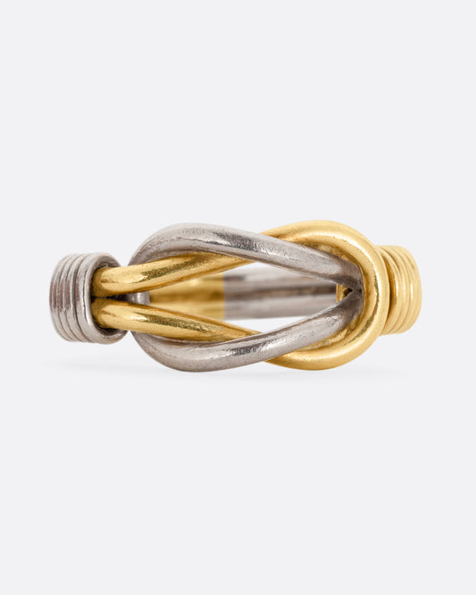 A white and yellow gold infinity knot ring. Shown from the front.