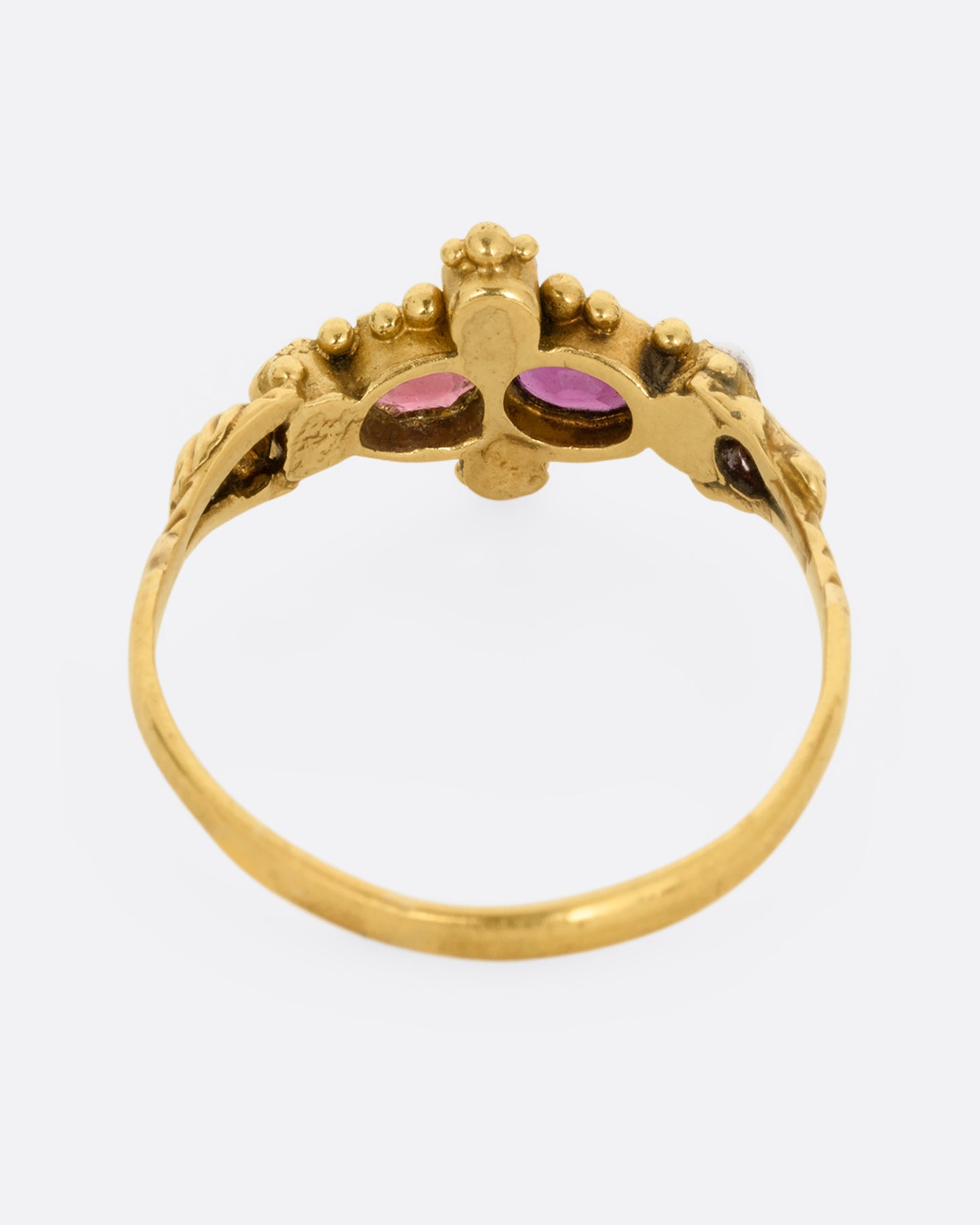 A yellow gold ring with garnets and seed pearls. Shown from the back.