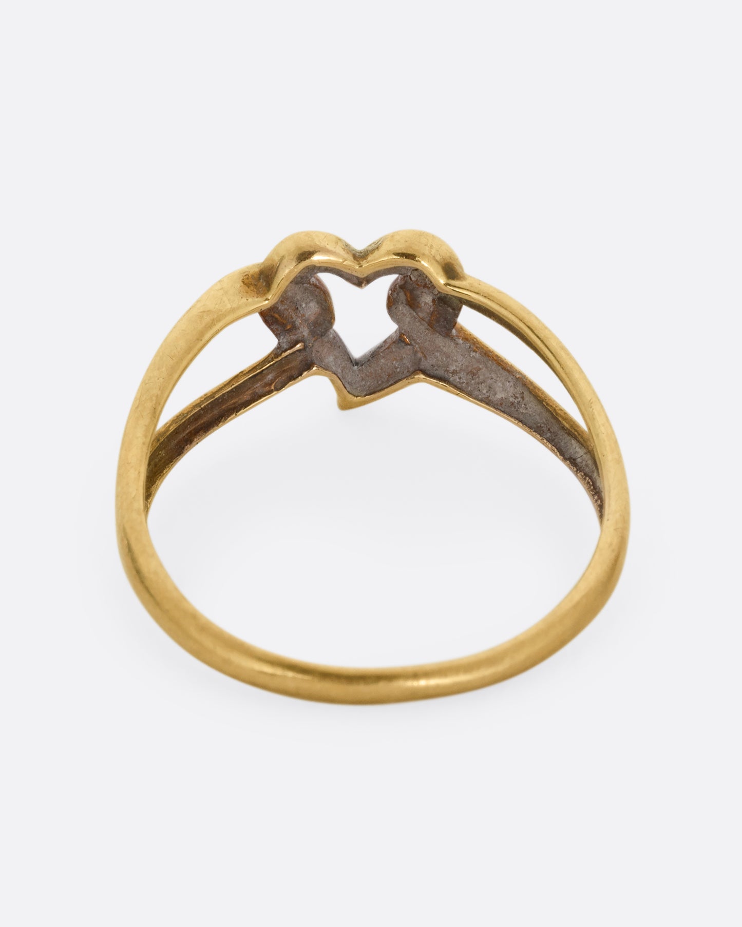 A yellow and white gold ring with an open heart and looped shoulders. Shown from the back.