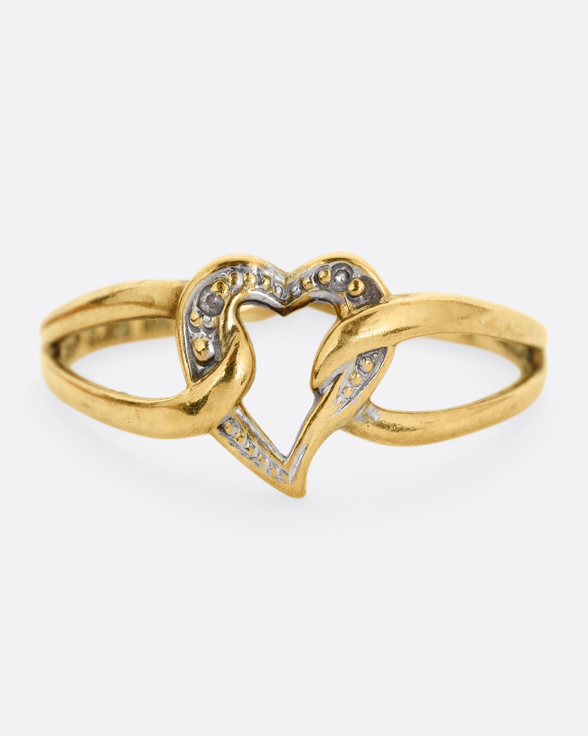 A yellow and white gold ring with an open heart and looped shoulders. Shown from the front.