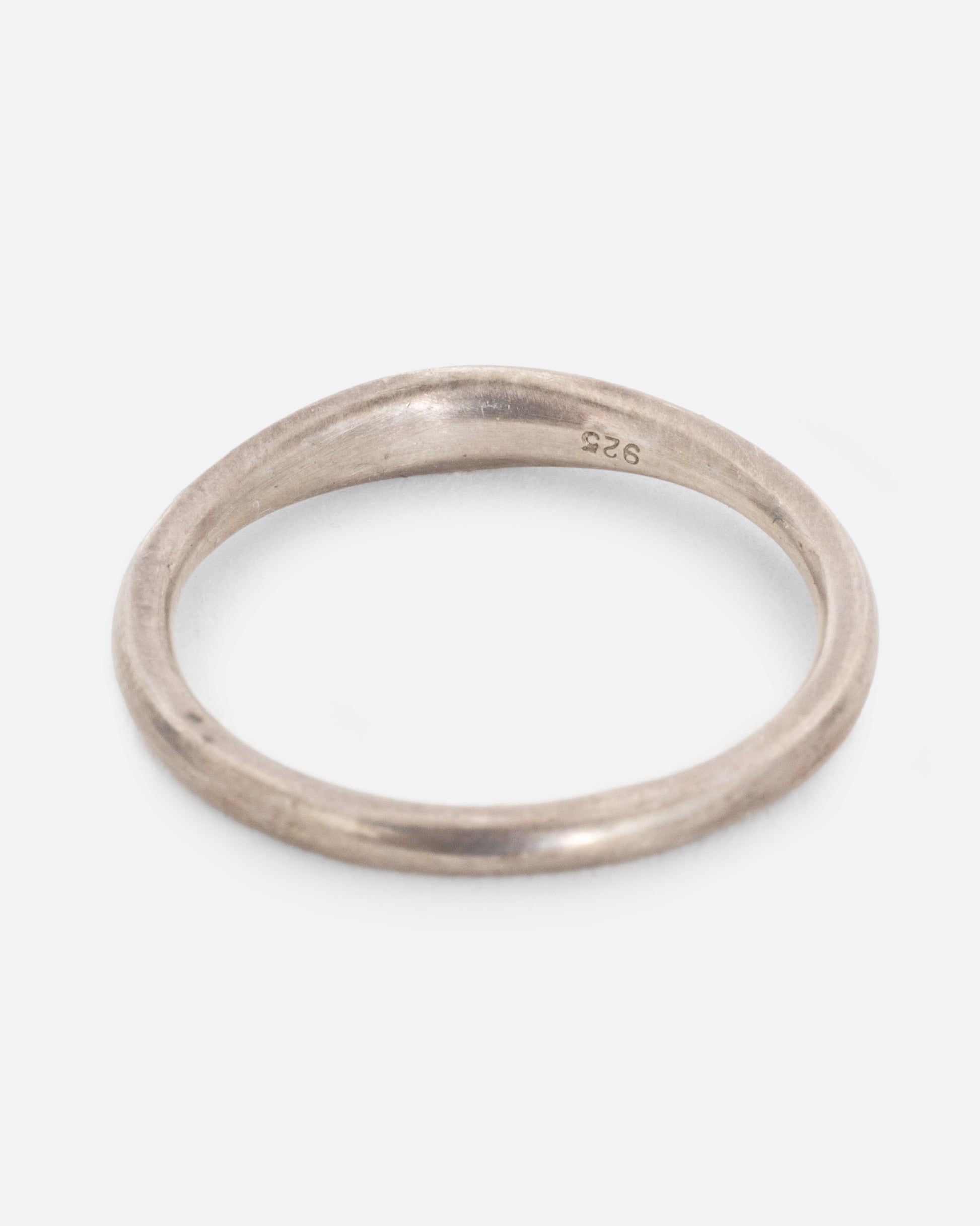 A silver ring with white diamonds and darkened engravings. Shown from the back.