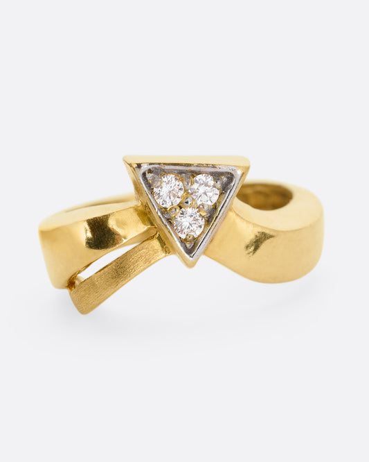 A yellow gold ring with a curvy band and three diamonds set in a triangular shaped setting. Shown from the front.